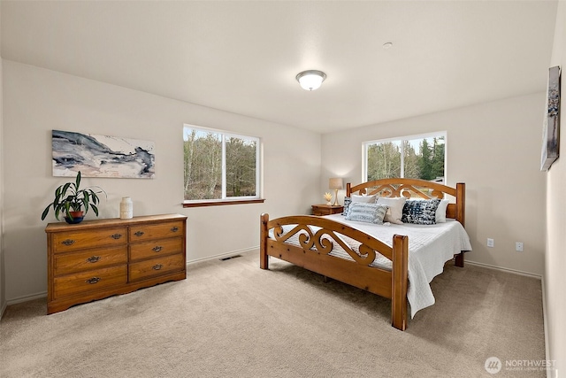 bedroom with visible vents, multiple windows, light colored carpet, and baseboards