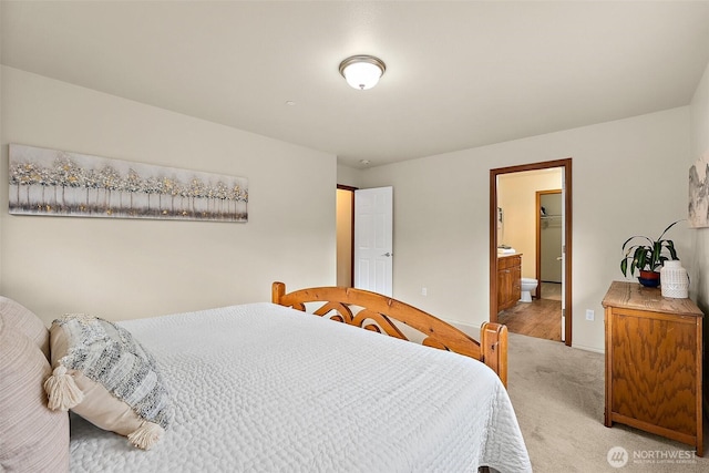 bedroom with baseboards, light carpet, and ensuite bath