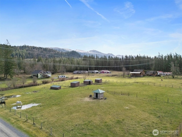 view of yard with a mountain view, a rural view, a wooded view, and fence