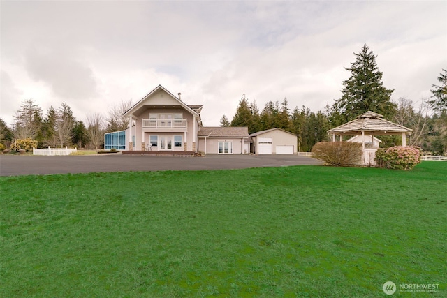 back of house featuring a garage, a gazebo, and a yard