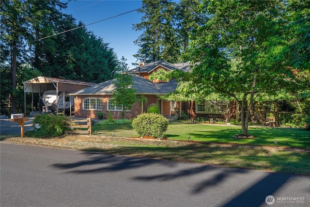 view of front of house with a detached carport, driveway, brick siding, and a front yard