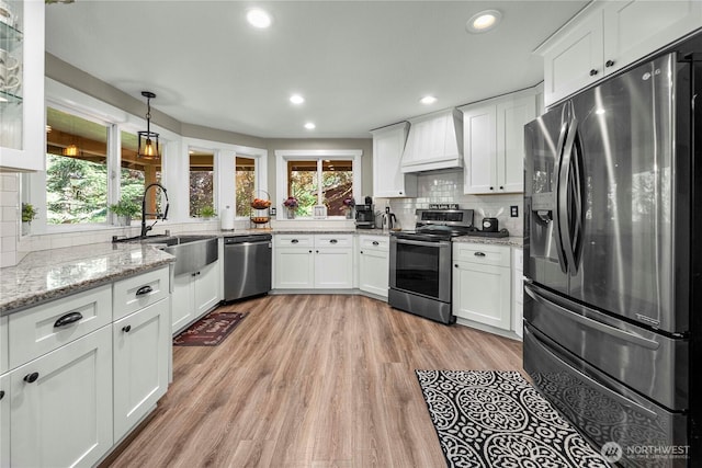 kitchen featuring a sink, custom range hood, white cabinetry, and stainless steel appliances