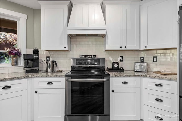 kitchen with custom exhaust hood, stainless steel electric stove, white cabinetry, and decorative backsplash