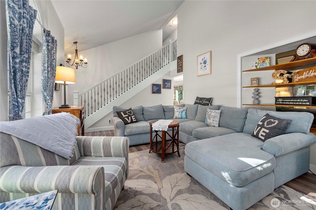 living area featuring a chandelier, stairway, a towering ceiling, and wood finished floors