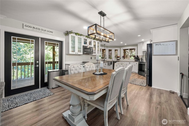 dining space with a notable chandelier, recessed lighting, french doors, and light wood-type flooring