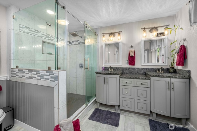 full bath featuring double vanity, a stall shower, and a sink