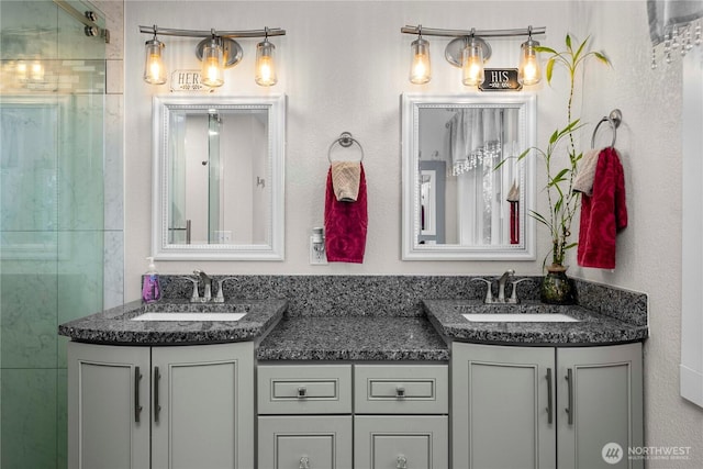 bathroom with double vanity, a shower with shower door, and a sink