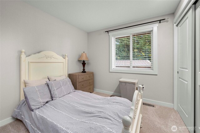 carpeted bedroom with a closet, visible vents, and baseboards