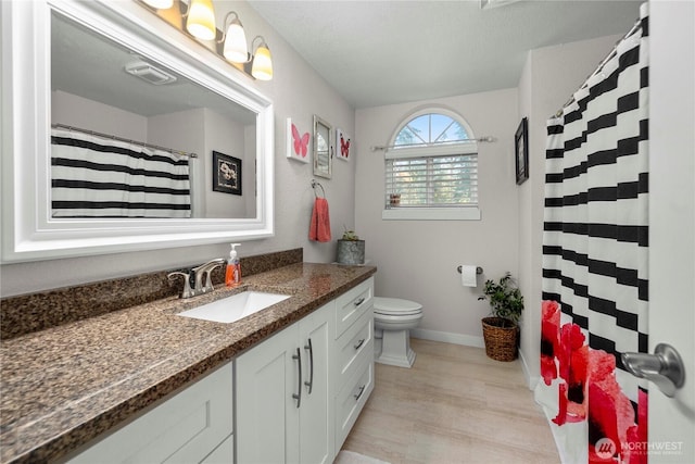 full bathroom with toilet, wood finished floors, a shower with shower curtain, baseboards, and vanity