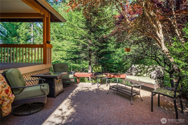 view of patio featuring an outdoor living space with a fire pit and a view of trees