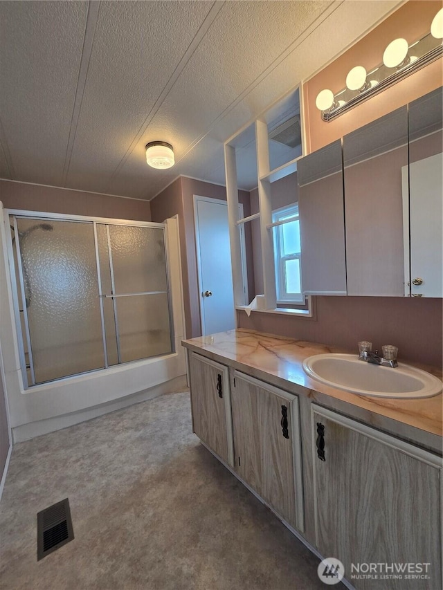 full bathroom with a shower with door, visible vents, a textured ceiling, and vanity