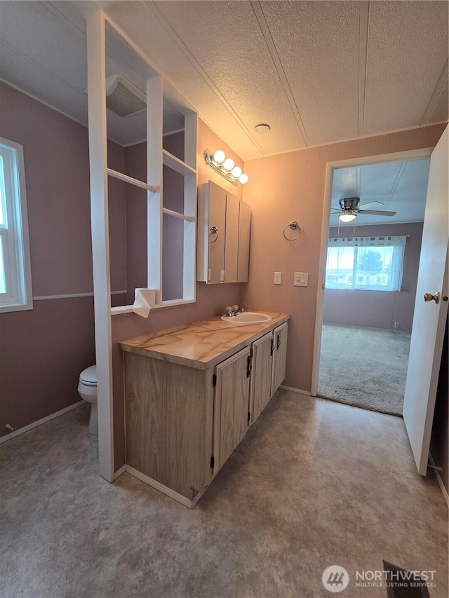 bathroom featuring a textured ceiling, ceiling fan, vanity, and toilet