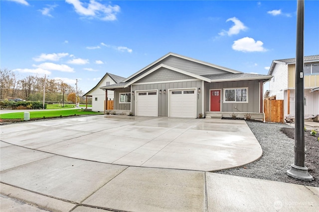 view of front facade featuring driveway, board and batten siding, an attached garage, and fence