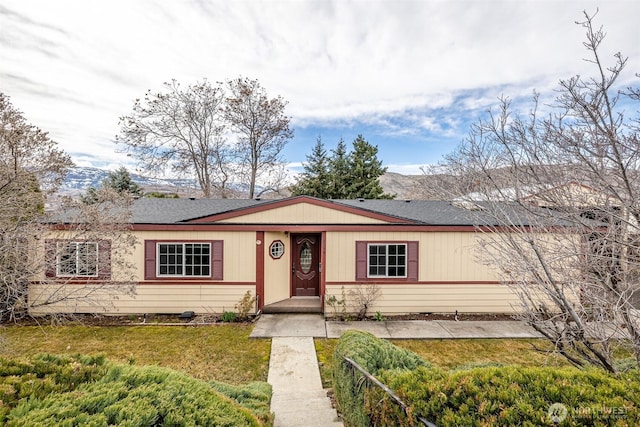 view of front of house with a front yard and a shingled roof