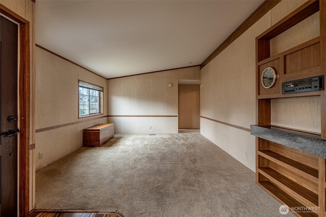 spare room with ornamental molding, wallpapered walls, lofted ceiling, and carpet floors