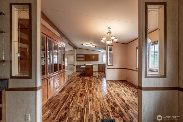 kitchen featuring wallpapered walls, lofted ceiling, dark wood-style flooring, white dishwasher, and a notable chandelier