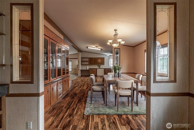 dining room with an inviting chandelier, vaulted ceiling, plenty of natural light, and dark wood-style flooring