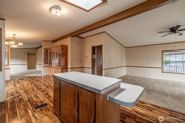 kitchen with a center island, open floor plan, lofted ceiling with beams, ceiling fan with notable chandelier, and wood finished floors