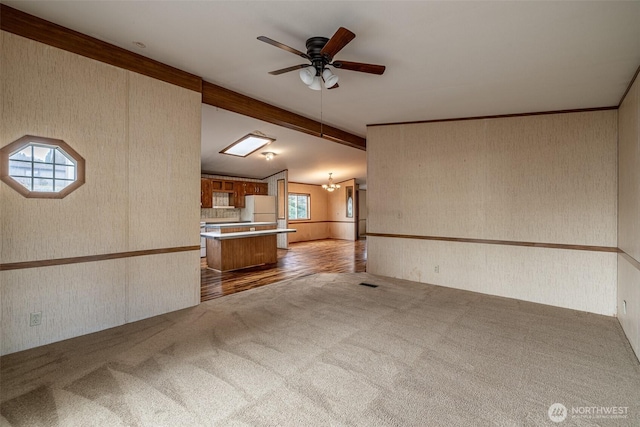 interior space with lofted ceiling with beams, carpet, ceiling fan, and wallpapered walls