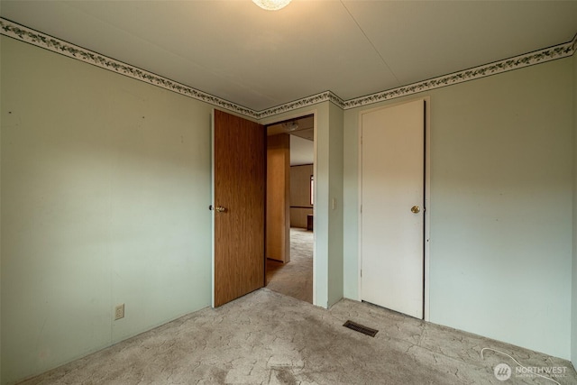 unfurnished bedroom featuring a closet, visible vents, and carpet