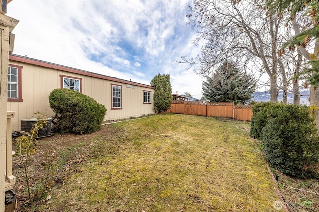 view of yard with central AC and fence