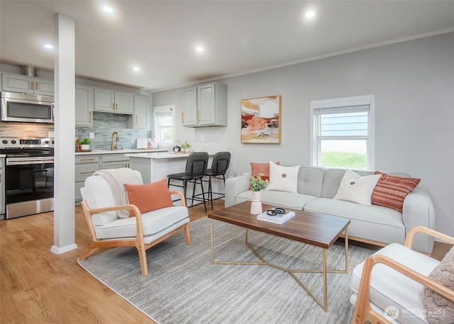 living area featuring recessed lighting, light wood-style flooring, and ornamental molding