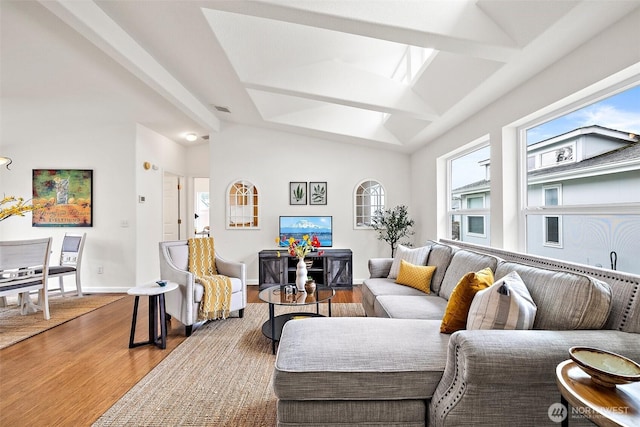 living area featuring visible vents, baseboards, wood finished floors, and vaulted ceiling with beams