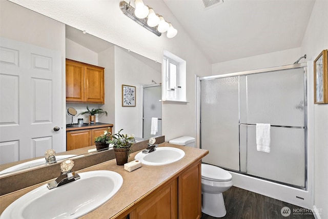 bathroom featuring a sink, toilet, and a shower stall