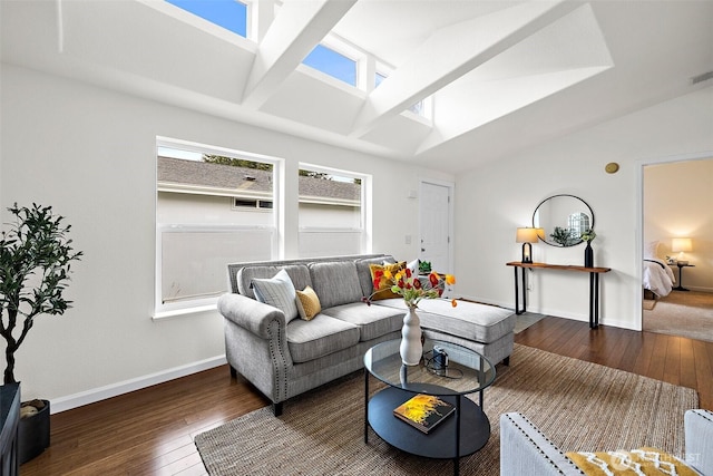 living area featuring visible vents, vaulted ceiling with skylight, baseboards, and hardwood / wood-style flooring