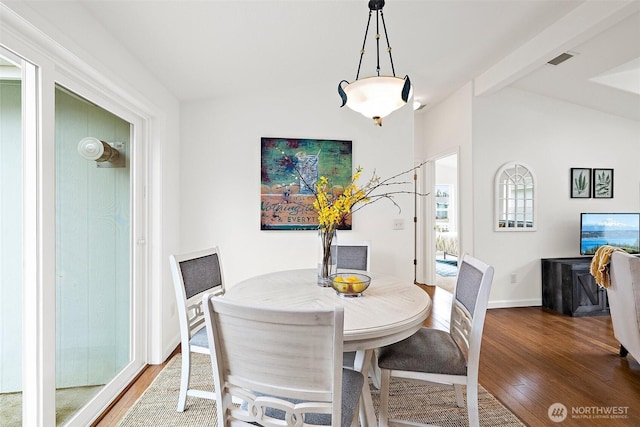 dining room featuring lofted ceiling with beams, visible vents, baseboards, and wood finished floors