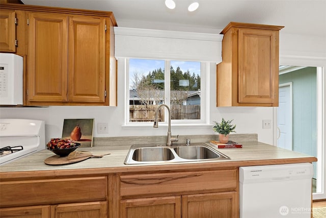 kitchen featuring white appliances, light countertops, and a sink