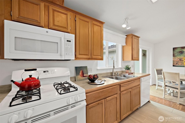 kitchen featuring light countertops, light wood-style flooring, brown cabinetry, white appliances, and a sink