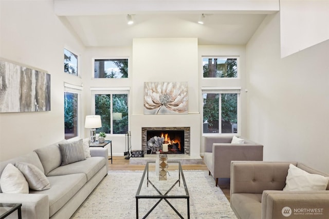 living area featuring plenty of natural light, a lit fireplace, and high vaulted ceiling