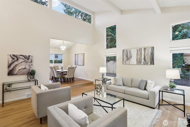 living area with beamed ceiling, baseboards, high vaulted ceiling, and wood finished floors