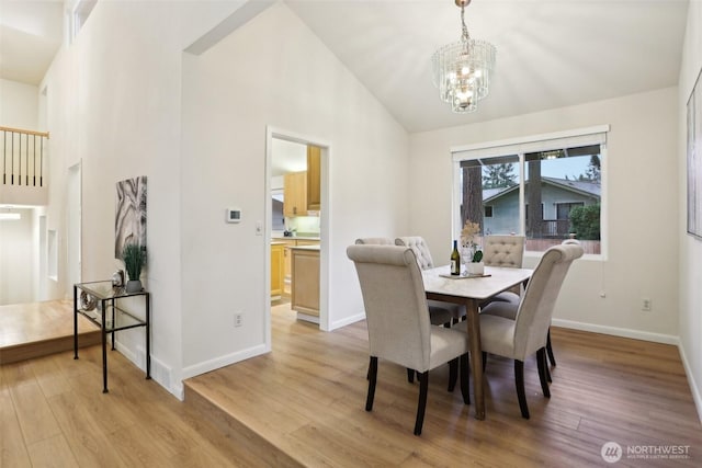 dining space with a chandelier, high vaulted ceiling, light wood-type flooring, and baseboards