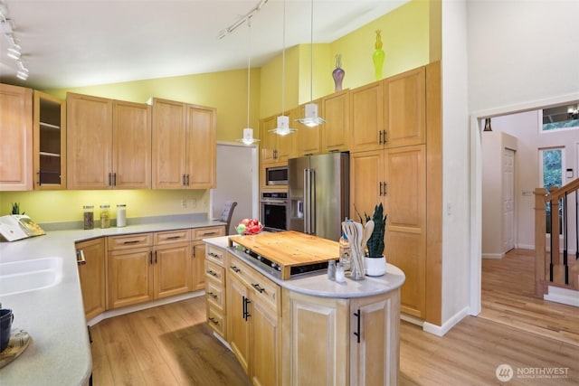 kitchen featuring high vaulted ceiling, light wood-style flooring, a kitchen island, appliances with stainless steel finishes, and light countertops