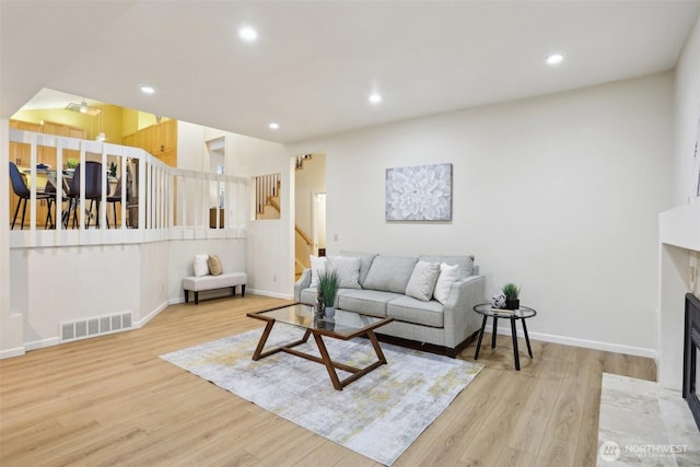 living area with visible vents, wood finished floors, recessed lighting, a fireplace, and stairs