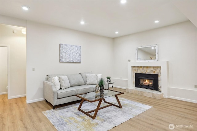 living area with recessed lighting, baseboards, light wood-style floors, and a fireplace