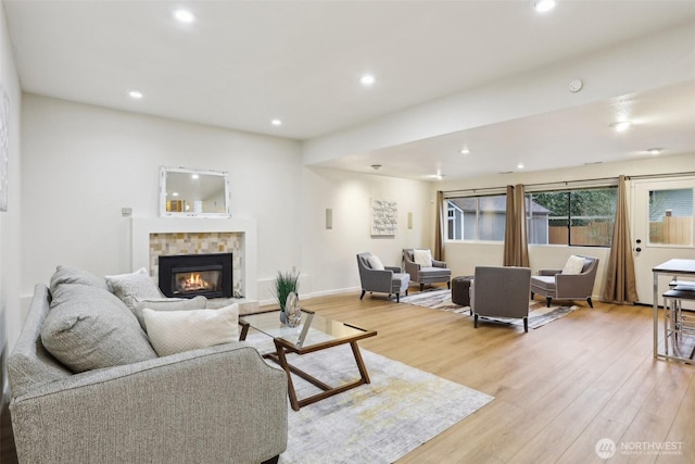 living area with recessed lighting, baseboards, light wood-style floors, and a tiled fireplace