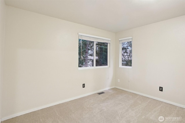 unfurnished room featuring visible vents, light carpet, and baseboards