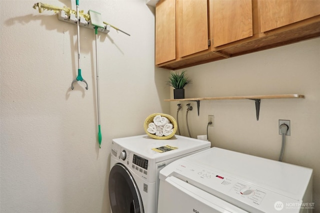 clothes washing area featuring washer and dryer and cabinet space