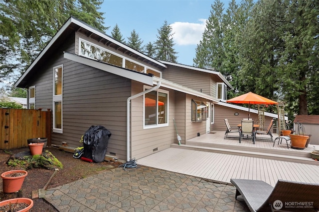 back of property with a deck, outdoor dining space, and fence