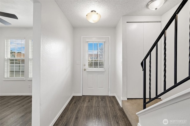 entryway with stairs, wood finished floors, baseboards, and a textured ceiling