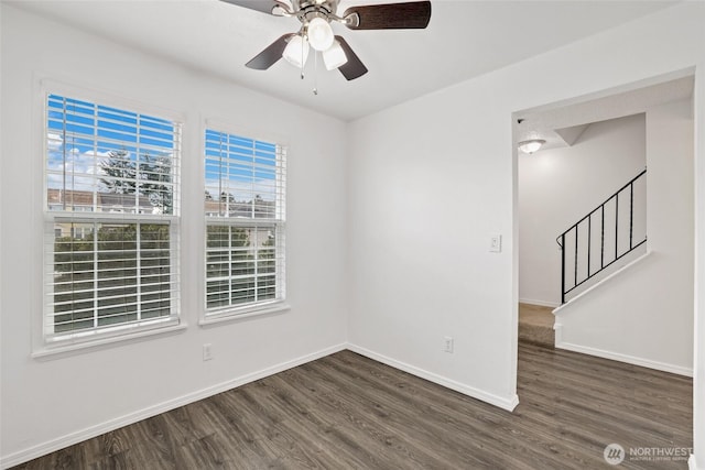 empty room with a ceiling fan, stairs, baseboards, and wood finished floors