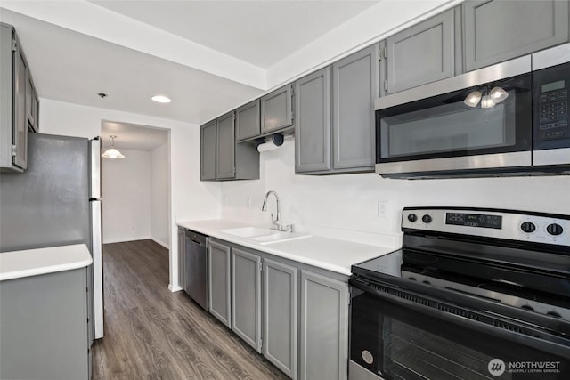 kitchen with dark wood-style floors, gray cabinetry, a sink, light countertops, and appliances with stainless steel finishes