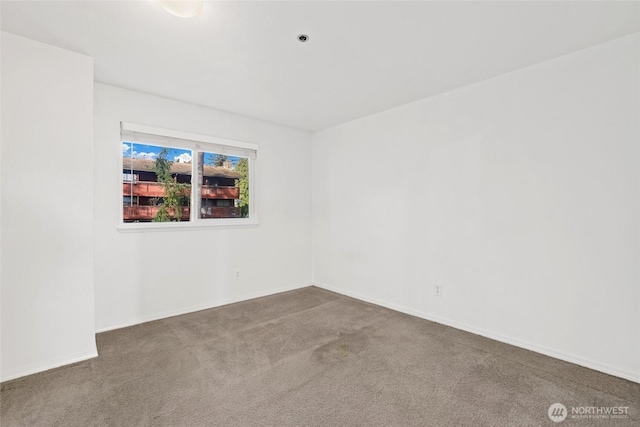 spare room featuring carpet flooring and baseboards