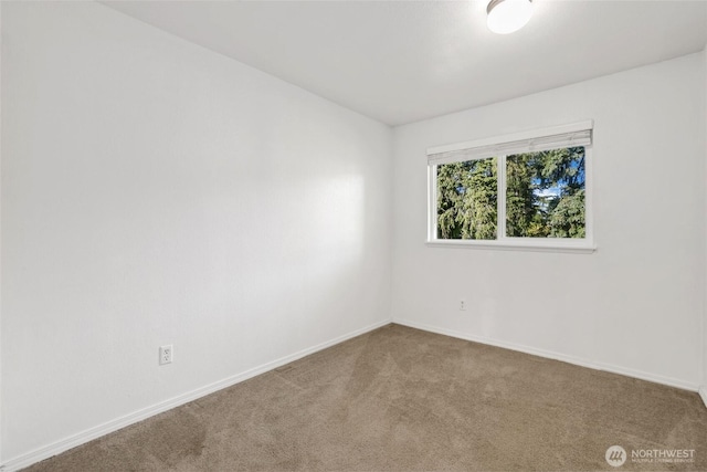 spare room featuring carpet flooring and baseboards