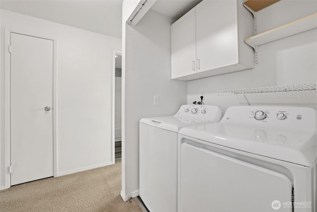 clothes washing area featuring washer and dryer, baseboards, cabinet space, and light carpet