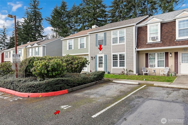 view of property featuring a residential view, uncovered parking, a chimney, and a shingled roof