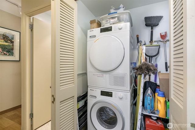 laundry room featuring wood finished floors, laundry area, and stacked washer / dryer